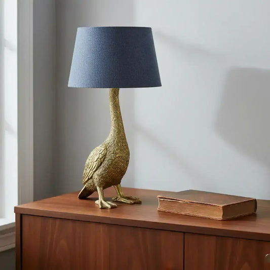 Decorative goose-shaped table lamp with a dark blue shade on a wooden surface.
