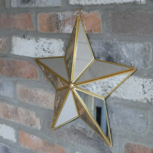 Gold star-shaped mirror hanging on a brick wall
