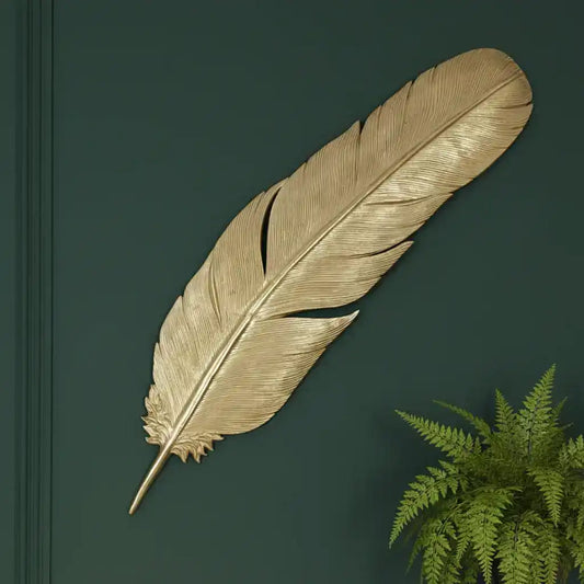 Decorative gold feather on a dark green background with a plant