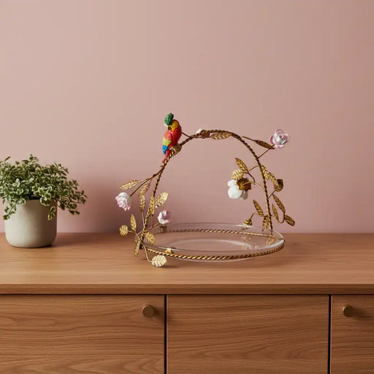 Decorative plate with gold leaf design, bird figurine, and flowers on a white background