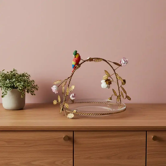 Decorative plate with gold leaf design, bird figurine, and flowers on a white background