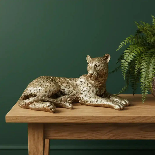 Gold panther figurine on a wooden surface with a stone wall background