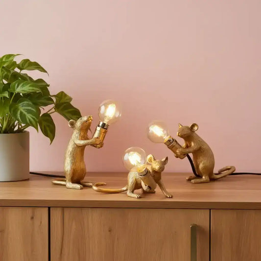 Decorative lamp with animal figures holding light bulbs on a book against a beige background