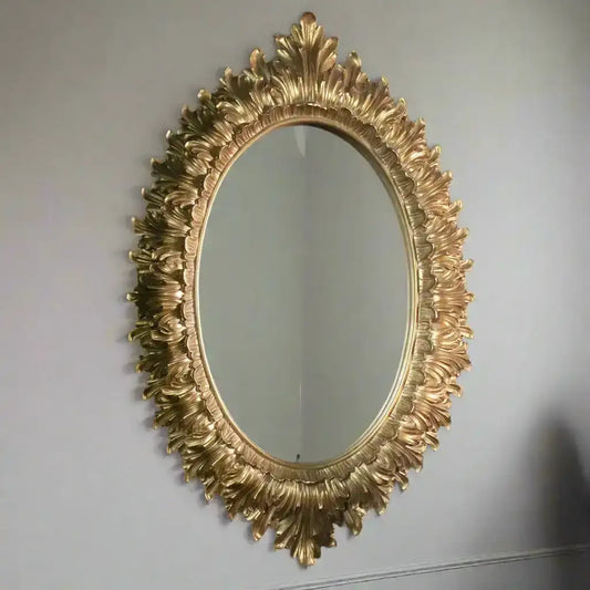 Decorative gold mirror with intricate design on a plain wall