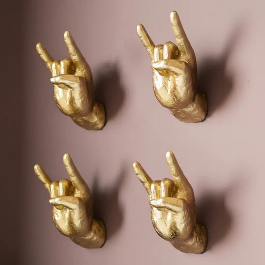 Four gold hands making rock-on gestures on a brown background