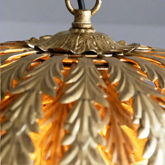 Close-up of a gold decorative lamp with intricate leaf patterns.