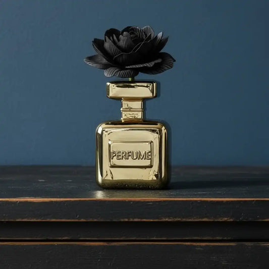 Gold perfume bottle with a black rose on top against a blue background
