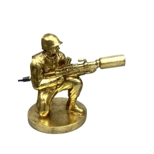 Gold-colored figurine of a soldier with a weapon on a white background