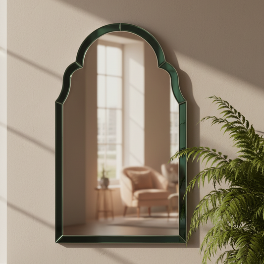 Arched mirror with green frame on a wall with a plant in the foreground
