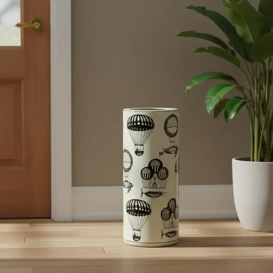 Umbrella stand with hot air balloon design on a wooden floor next to a plant