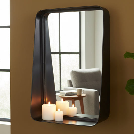 Rectangular mirror with a black frame on a gray wall, reflecting candles.