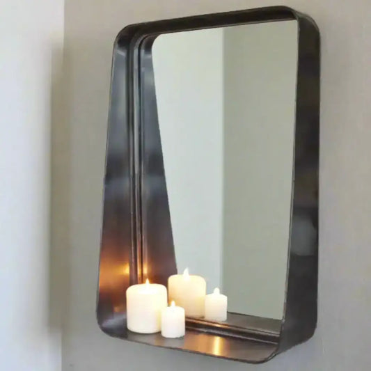Rectangular mirror with a black frame on a gray wall, reflecting candles.