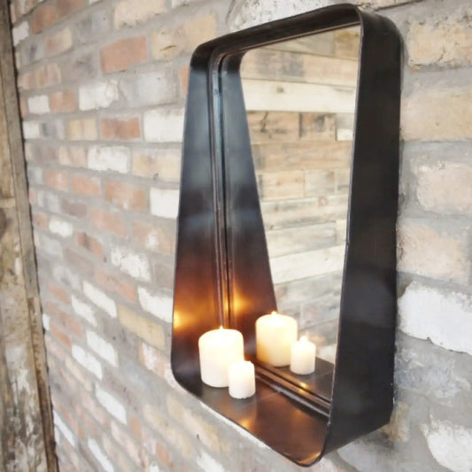 Decorative wall mirror with candles inside, mounted on a brick wall.