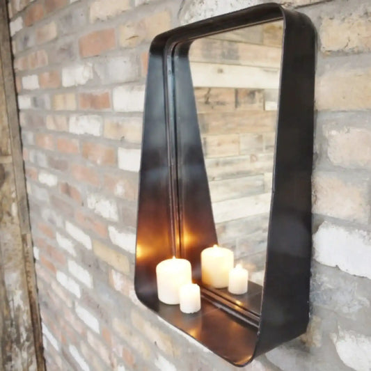 Decorative wall mirror with candles inside, mounted on a brick wall.
