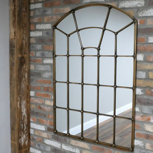Decorative window-style mirror on a brick wall