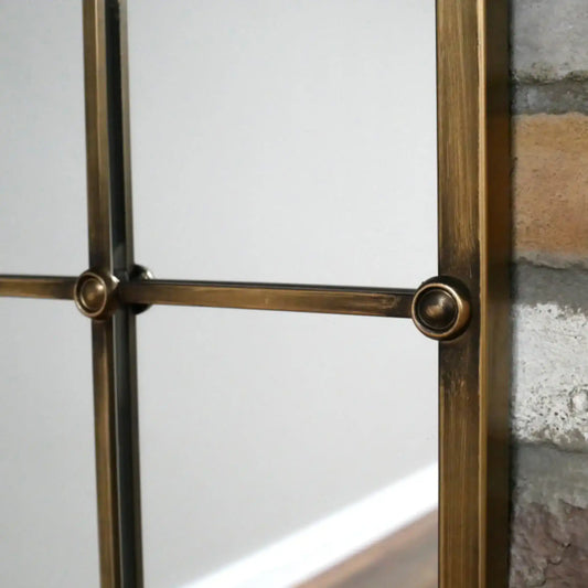 Decorative metal frame with glass panel against a stone wall.