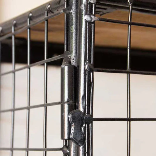 Close-up of a metal wire cage with a latch on a blurred background