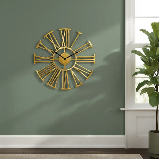 Gold wall clock on a green wall with a plant in the corner
