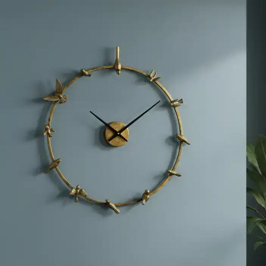 Decorative wall clock with gold branch design on a blue wall