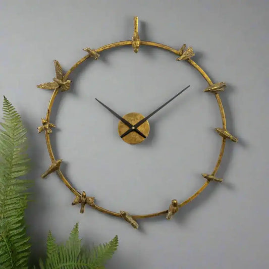 Decorative wall clock with gold branch-like design on a gray background