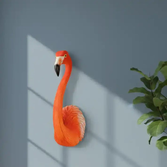 Decorative flamingo wall art against a gray wall with a plant on the right.