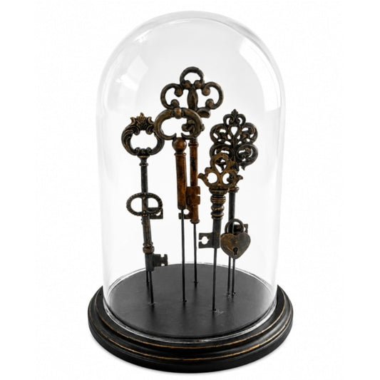 A set of five antique-style decorative keys displayed inside a clear glass dome cloche on a round black base, photographed against a plain white background.