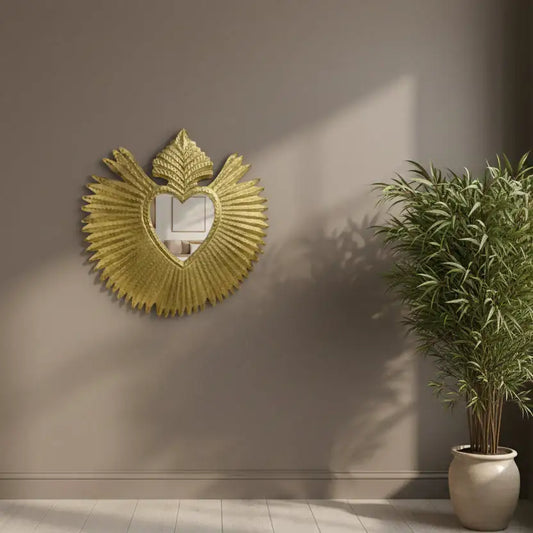 Decorative gold mirror on a wall with a potted plant beside it