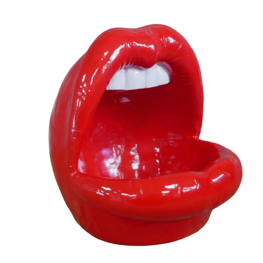 Red lips-shaped chair on a wooden surface with a stone wall background