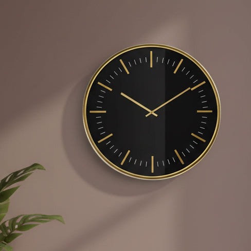 Black wall clock with gold accents on a white background