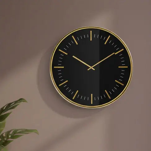 Black wall clock with gold accents on a white background