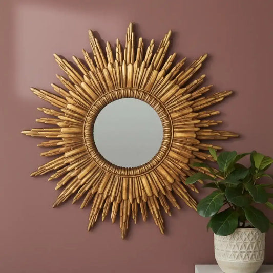 Decorative gold sunburst mirror on a brown wall with a plant in the corner.