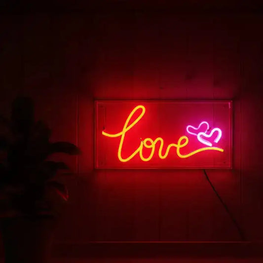Neon sign with 'love' and heart symbol on a dark background