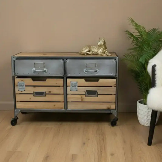 Wooden dresser with metal drawers in a room with a plant and chair.