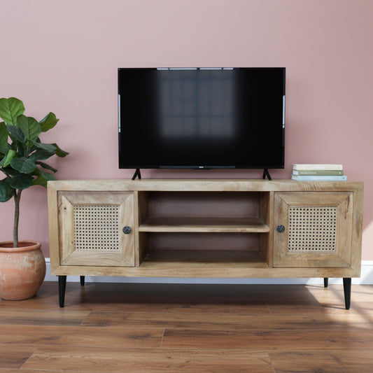 Wooden TV stand with rattan doors on a wooden floor against a gray wall.