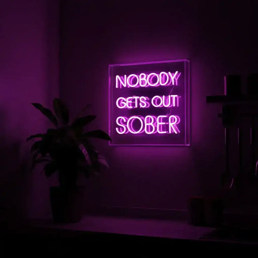 Neon sign with 'Nobody Gets Out Sober' text in a dark room with purple lighting.