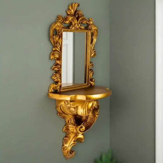 Decorative gold wall mirror with shelf against a green wall