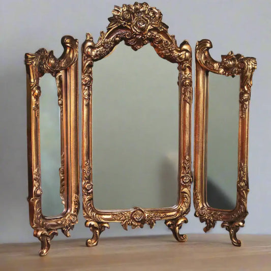 Ornate gold mirror set on a plain background