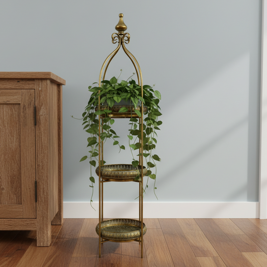 Decorative gold plant stand with green plants against a light gray wall.