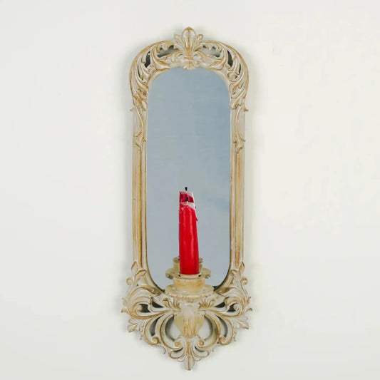 Decorative wall mirror with a candle holder on a white background