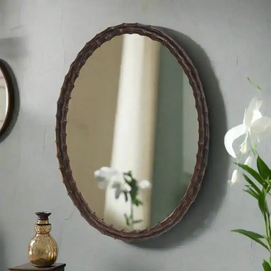 Oval mirror with a decorative brown frame on a white background