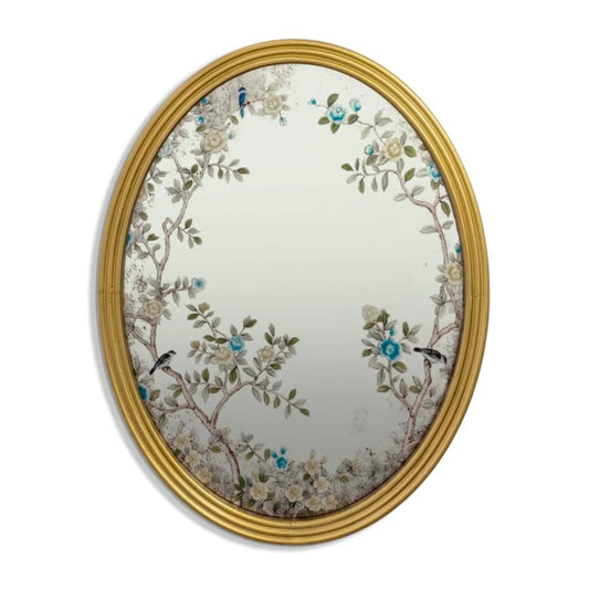 Decorative oval mirror with floral and bird design in a gold frame on a white background