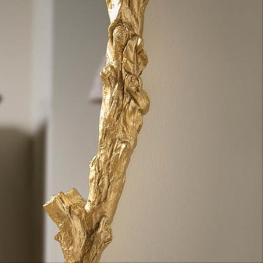 Gold leafed decorative branch against a neutral wall