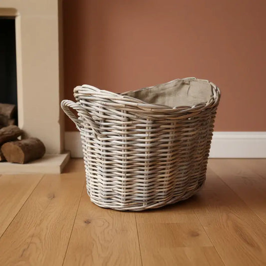 Wicker laundry basket on a wooden floor with a fireplace in the background