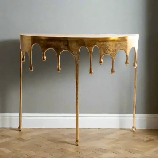 Gold console table with a unique design on a wooden floor and gray wall background