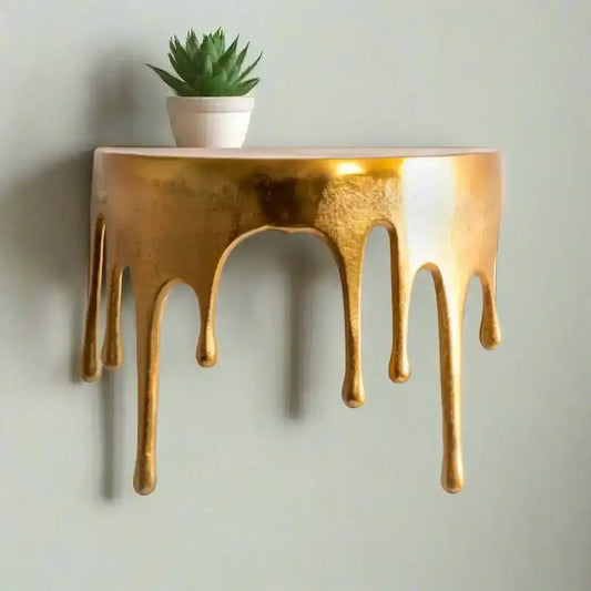 Decorative wall shelf with gold metallic finish and dripping effect on a white background