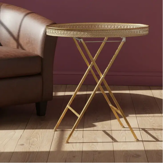 Gold side table with decorative tray next to a brown leather sofa against a purple wall.
