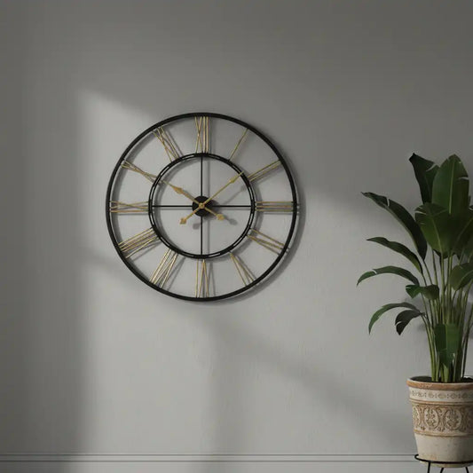 Large wall clock with gold accents on a gray wall next to a potted plant.