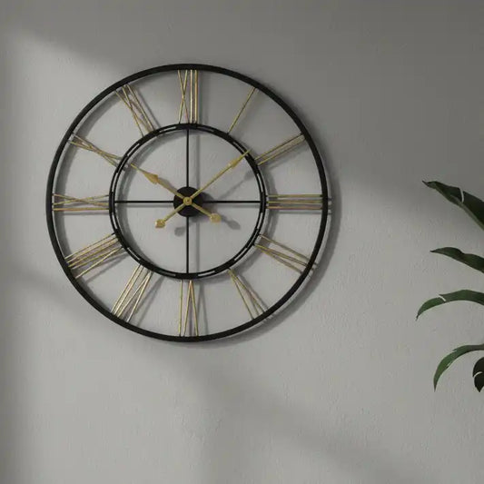 Large wall clock with gold Roman numerals on a gray wall.