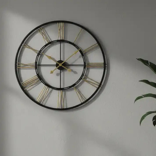 Large wall clock with gold Roman numerals on a gray wall.