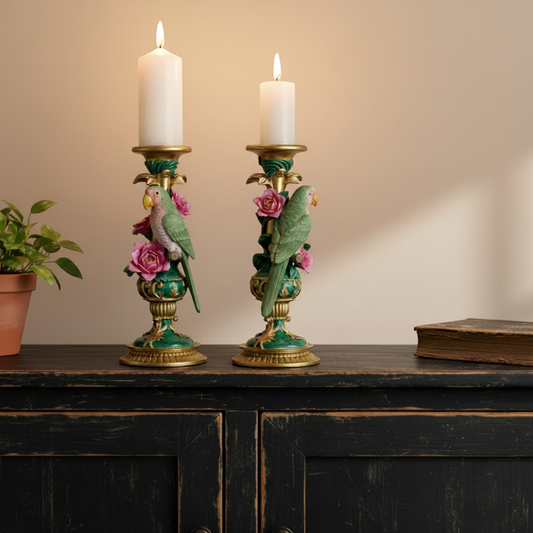 Decorative candle holders with parrot and flower designs on a wooden surface.
